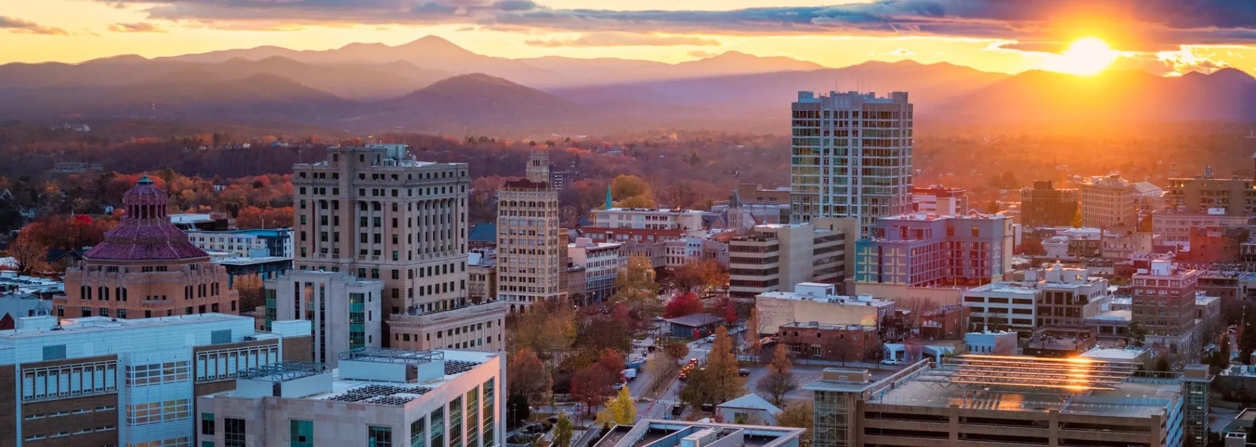 The sun rises behind downtown Asheville