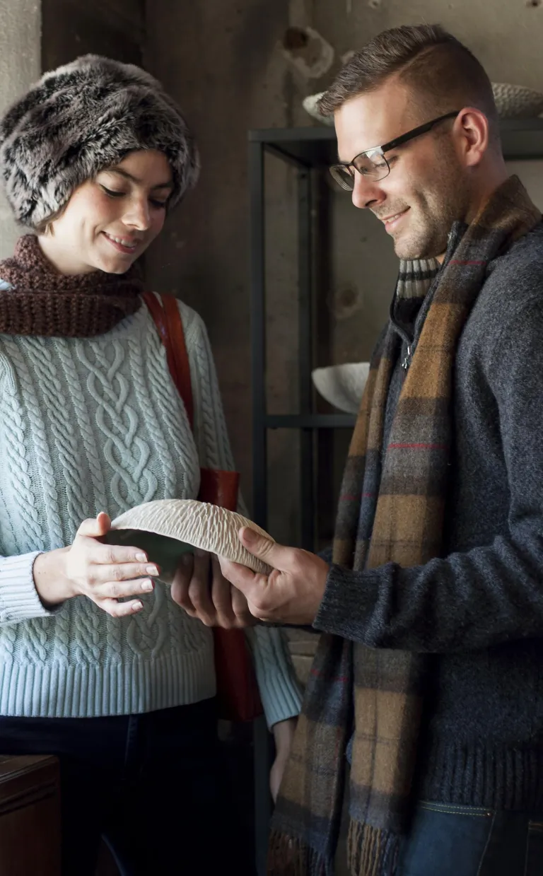 Two artists hold a ceramic bowl in Asheville