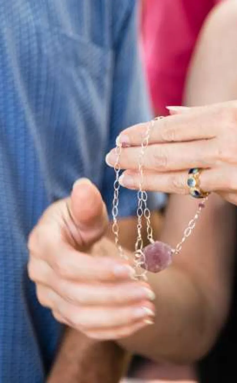 a person holds a necklace with a large purple stone in their hand in Asheville