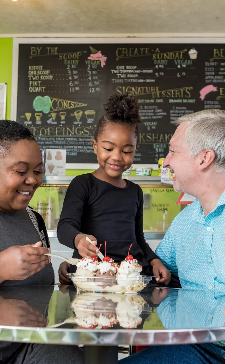 two parents smile with their child at a paint your own pottery shop