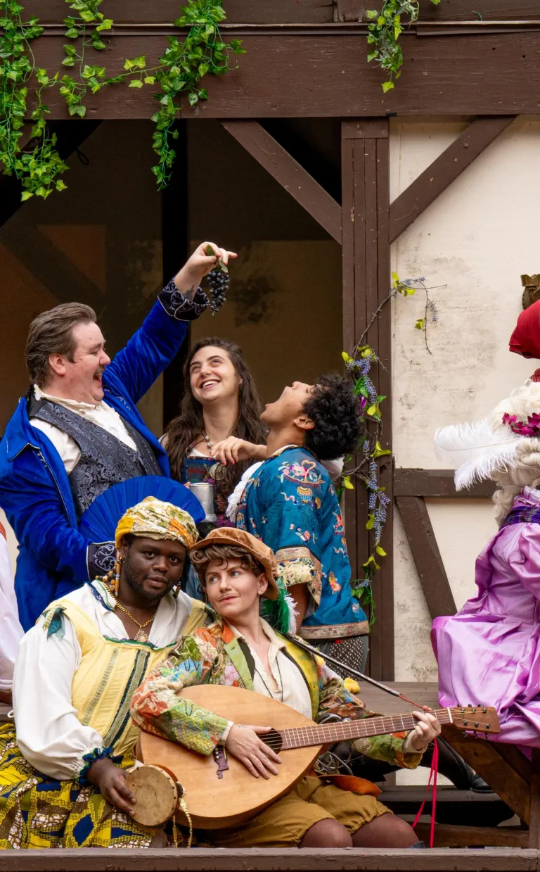 people in Sheakspearian costumes pose on a stage