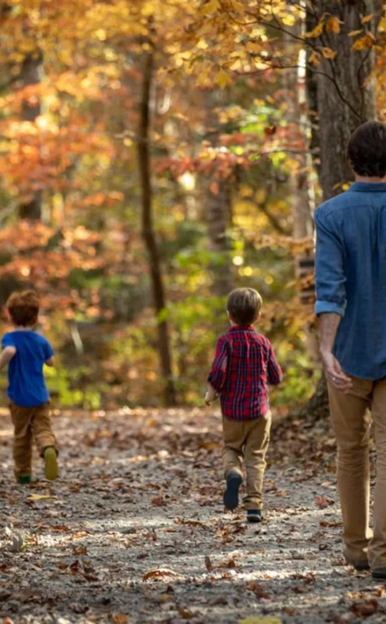 A family walks on a path surrounded by fall leaves in Asheville