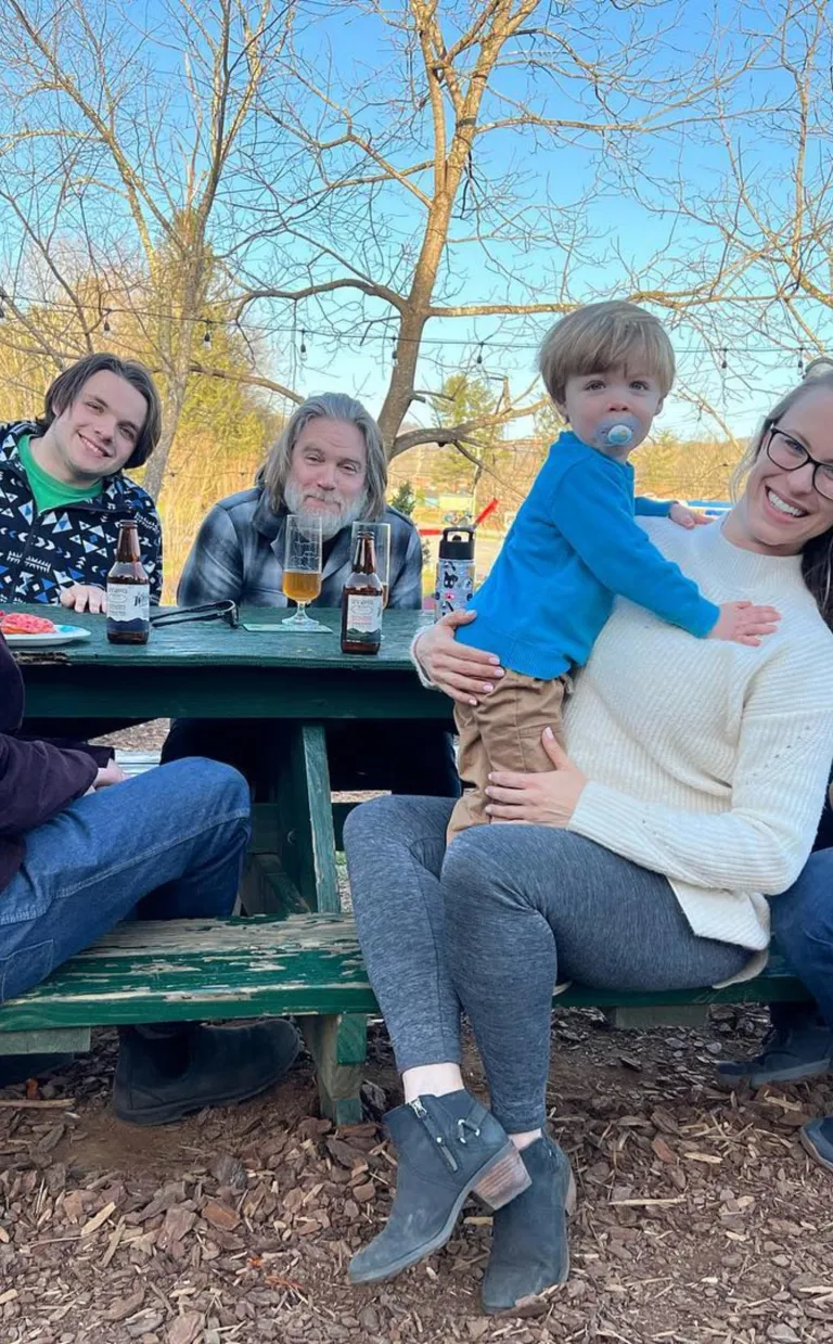 a family sits on a park bench smiling.